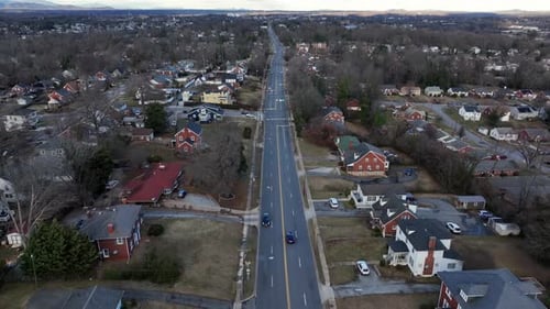 Driving car on main street of american neighborhood with leafless trees in winter. Aerial birds eye