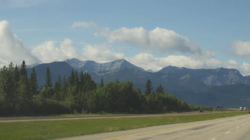 Driving on a highway next to majestic peaks of Rocky Mountains