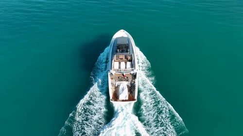 Aerial drone view of White motor yacht cruising on turquoise water with coastal view and mountains