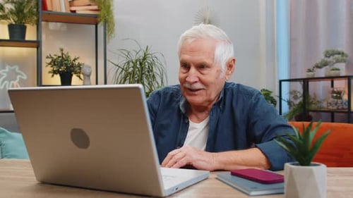 Happy Senior Old Man Grandfather Sitting on Sofa at Table Working on Laptop Pc at Office Home Room
