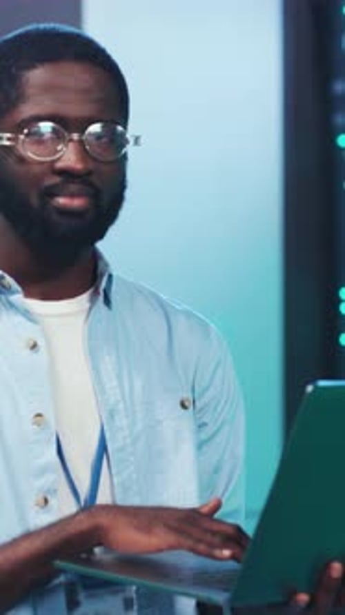 Smiling Man Working with Laptop in Server Room