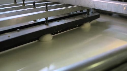 Boules de pâte crue transférées sur une bande transporteuse dans une fabrique de pain