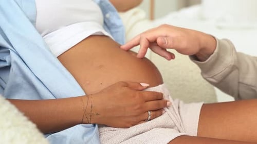 Pregnant multiethnic couple feels love and relax at home. Young expecting woman holds baby in pregna