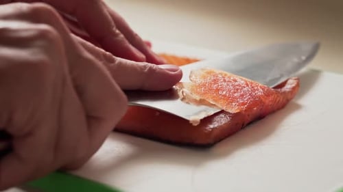 Salmon Being Carefully Trimmed on Cutting Board