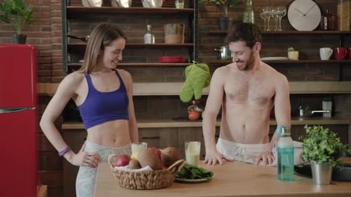 Athletic Couple Laughing in Kitchen After Healthy Workout