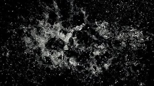 Water splashing and spreading on black background in close-up