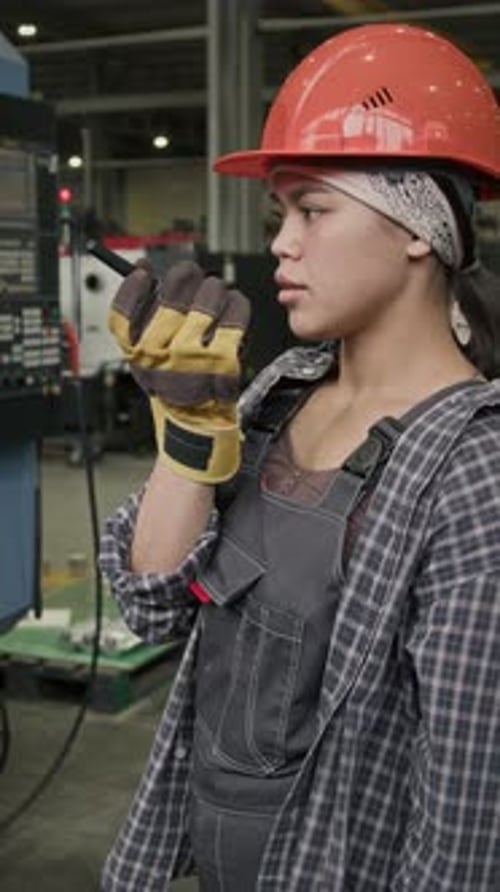 Vertical of Technician Communicating with Factory Workers via Walkie-Talkie