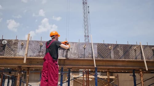 Vue arrière d'un ouvrier du bâtiment professionnel portant un casque de sécurité et une salopette qui fabrique un coffrage avec