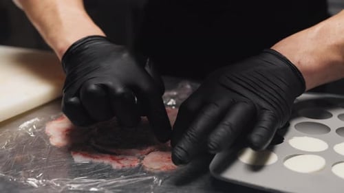 Gloved Hands Arranging Thin Slices of Meat