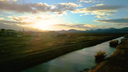 Picturesque River Flowing Through Meadow at Sunset
