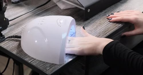 Woman dries nails under a special lamp for drying nails