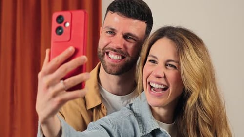 Cheerful Couple Posing for Selfie With Red Smartphone