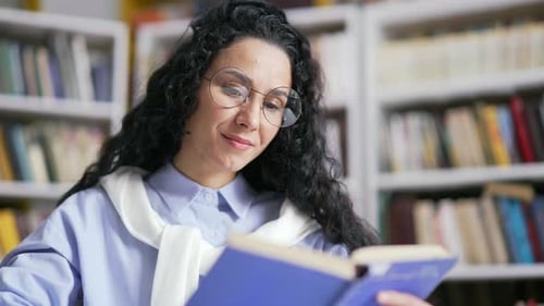 Close up. Female student learning reading book in campus library space. The girl is studying