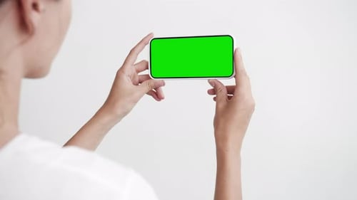 Young Person Use Smartphone with Green Screen Chroma Key Close-Up. Girl Hold