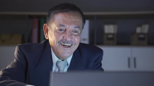 Man in Suit Looks at Computer and Claps