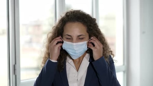 Woman Puts on Surgical Mask in Office