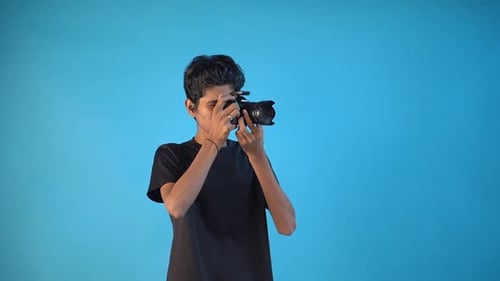 handsome young photographer looking into camera and adjusting the focus in photography studio blue b