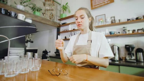 In a Quaint and Charming Cafe a Fatigued Barista Girl Takes a Moment to Rest By Leaning Against the