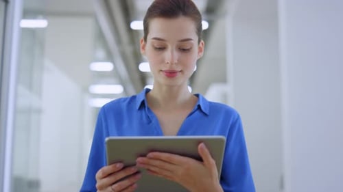 Beautiful Businesswoman Looking Tablet Screen While Walking on Modern Office. Happy Woman