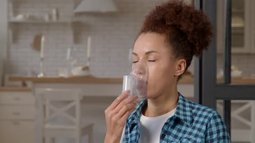 Woman Using Oxygen Mask in Bright Modern Kitchen