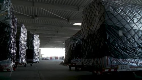 Intérieur sombre de l'entrepôt avec des rangées de palettes enveloppées dans du plastique noir, possibilité de stockage ou d'expédition