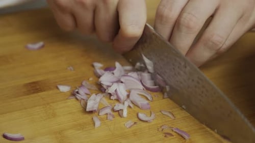 Chef slices onion on wooden cut board. Close up shot. slow motion.