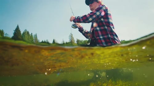Fly fishing. Angler casts the fly on the rapid river, footage with underwater view of the river