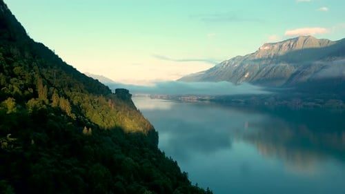 Drone flight over a beautiful Swiss alpine lake. The drone flies above the valley forest to reveal t