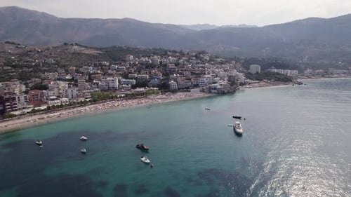 Aerial of boats calmly resting on the azure bay of Himara, Albania