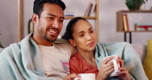 Smiling Couple Relaxing on Couch with Hot Drinks