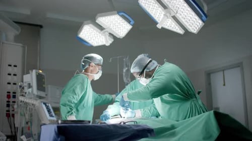 Diverse surgeons with face masks during surgery in operating room in slow motion