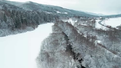Aerial Drone View Of Snowscape Countryside With Mountain River And Road During Winter.