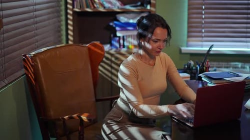 A Focused Woman Working Diligently Late at Night on Her Laptop in the Home Office Setting