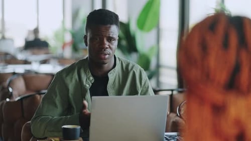 Man Talking at Table with Laptop