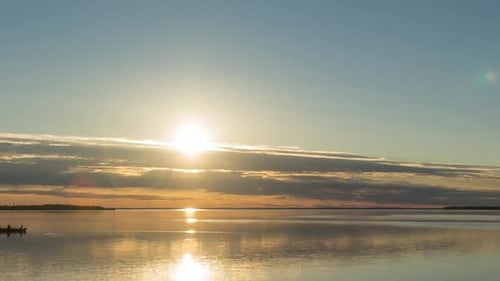 Beautiful sunset time lapse view of flat surface of large lake in Northern Ontario with fishermen in