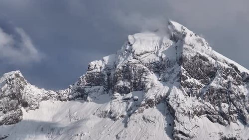 Slowly panning shot showing thick snow on rocky mountain during winter