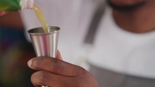 Barkeep Pours Juice Into Jigger at Bar Counter