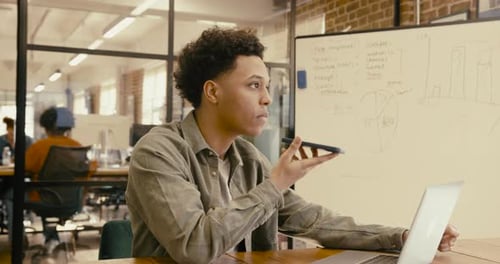 Young Adult Businessman Talking into Phone using AI Technology in Office