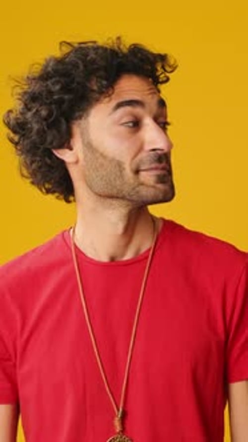 Surprised man looks to side to show copy-space isolated on yellow background in studio