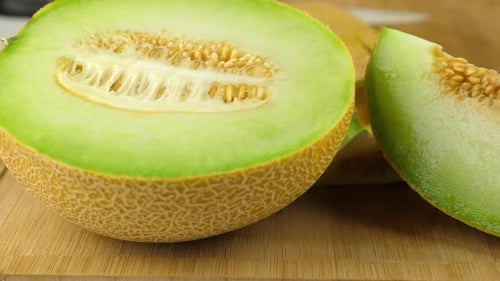 Photo de suivi d'un melon Galia juteux, sur une planche à découper en bambou