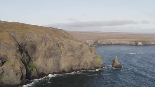 Aerial flight of along rocky coastline with Ketubjorg cliifs during sunny day on Iceland