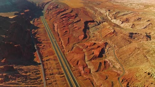 Rocky orange landscape crossed by the motorways with few cars moving by. Stunning scenery of canyons