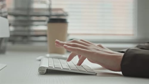 Hände einer Programmiererin, die auf einer drahtlosen Tastatur tippt