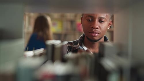 Man Chooses Book on Library Bookshelf