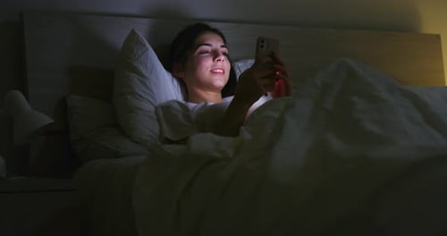 Close up of woman is using a smartphone before falling asleep for send messages and navigate on so