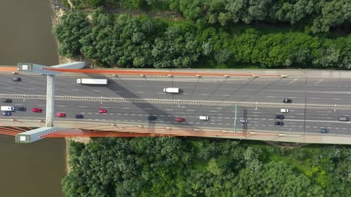 City car moving at highway bridge on background smooth river surface drone view