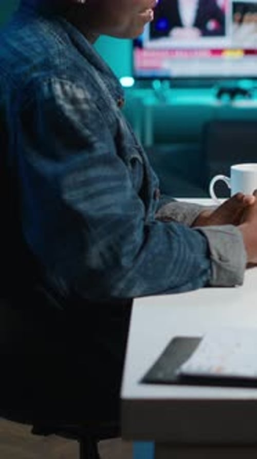 Young Adult Sips Drink in Front of Computer