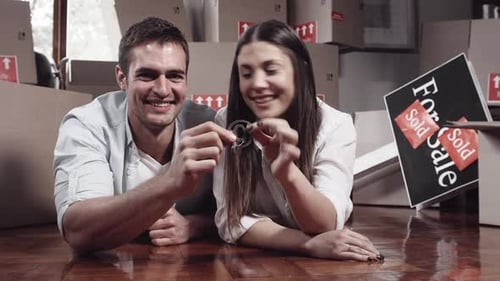 Couple Lying on Floor Smiling Holding Keys
