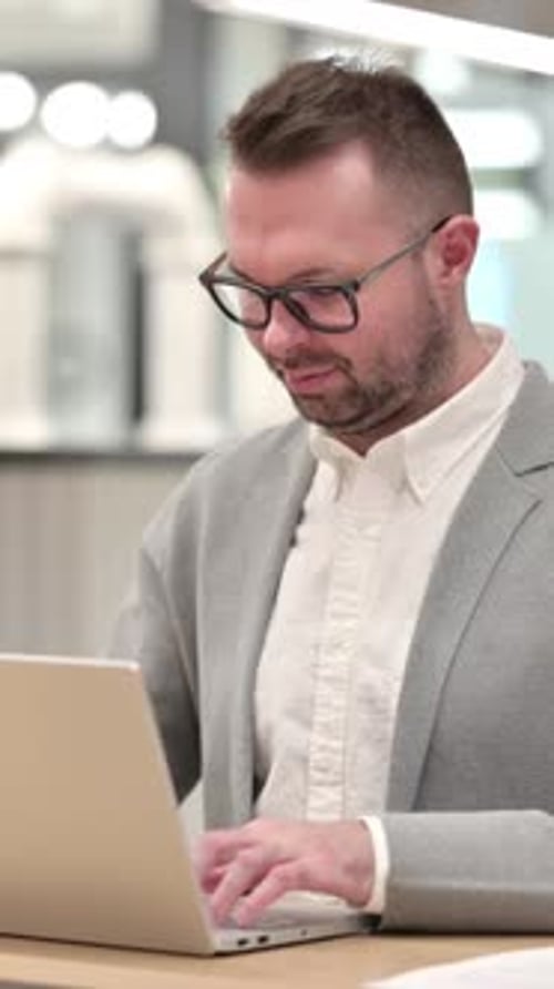 Man in Blazer Working on Laptop Gives Thumbs Up