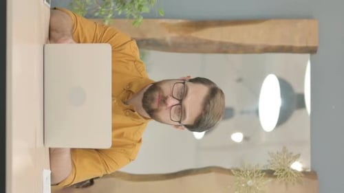 Vertical Video of Young Businessman Looking at Camera while using Laptop